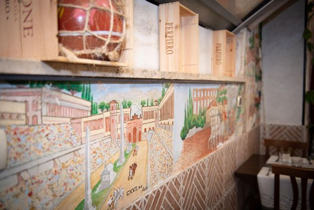 Parete decorata con un affresco di Roma e casse di vino, vicino al Colosseo