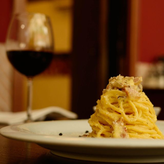 Spaghetti alla carbonara con un calice di vino rosso, vicino al Colosseo